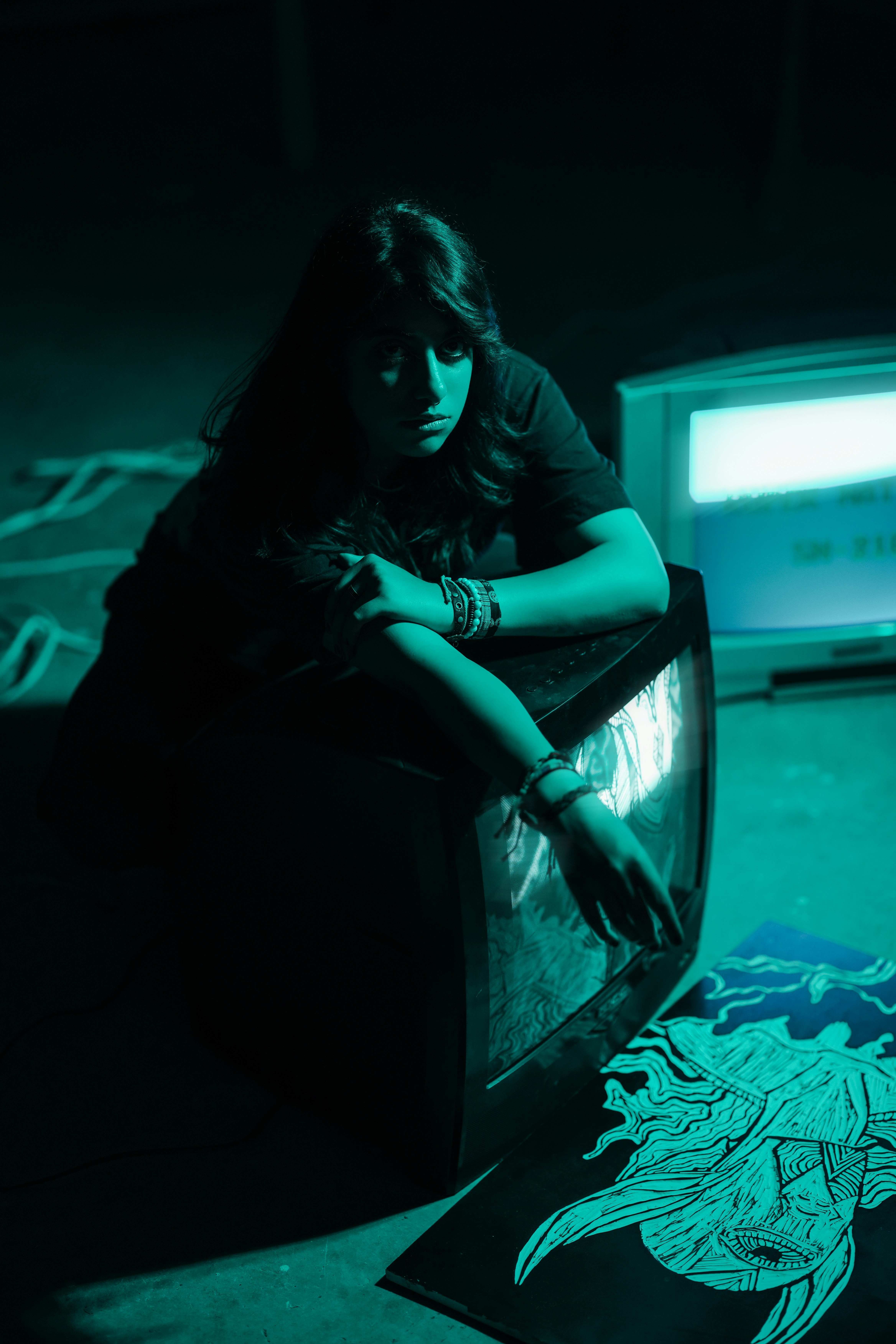 Woman poses with vintage television in dark room